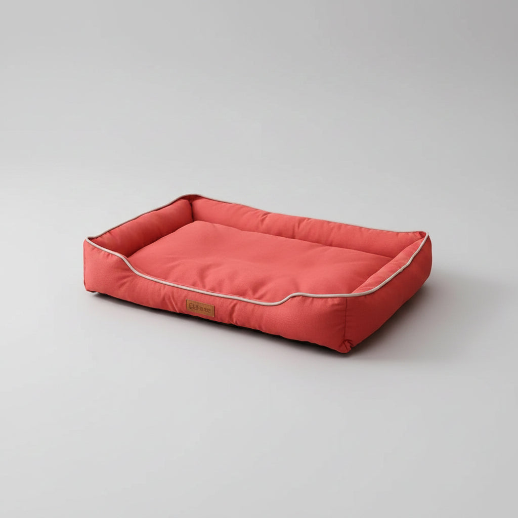 Red pet bed on a wooden floor with a plant and cabinet in the background