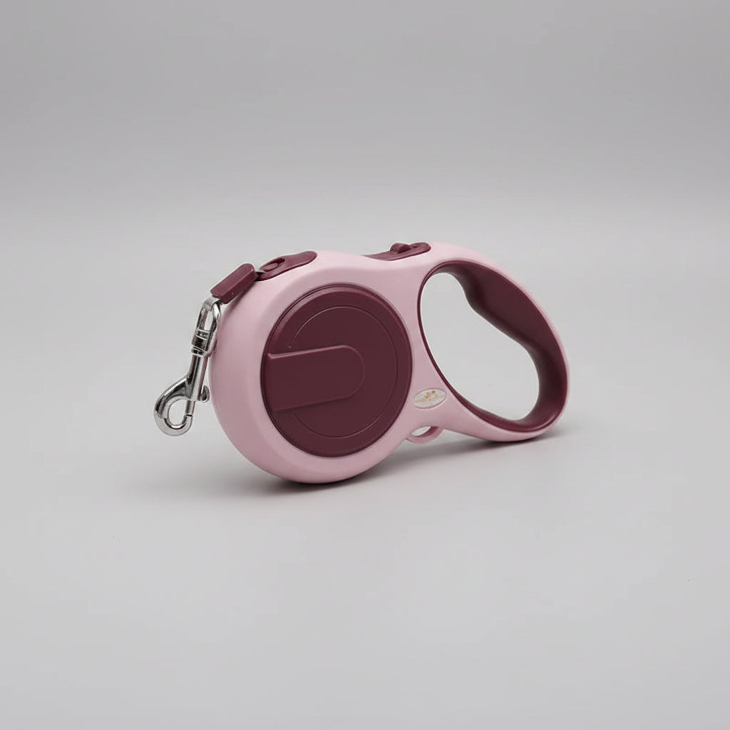 Pink and purple retractable dog leash on a white surface with a soft fabric background