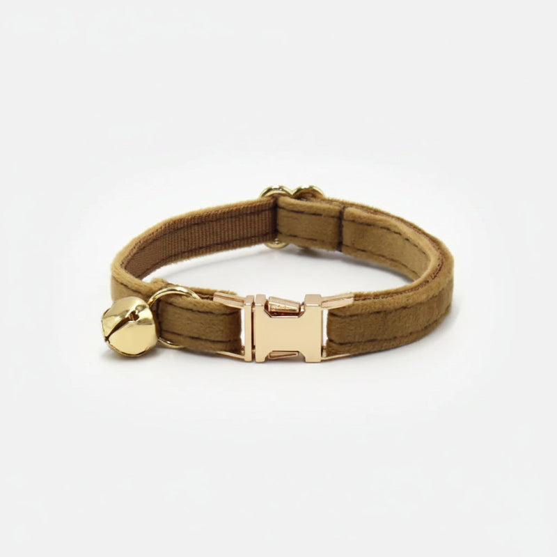 Camel velvet cat collar with polished gold hardware and bell styled in warm editorial lighting for modern luxury pets.