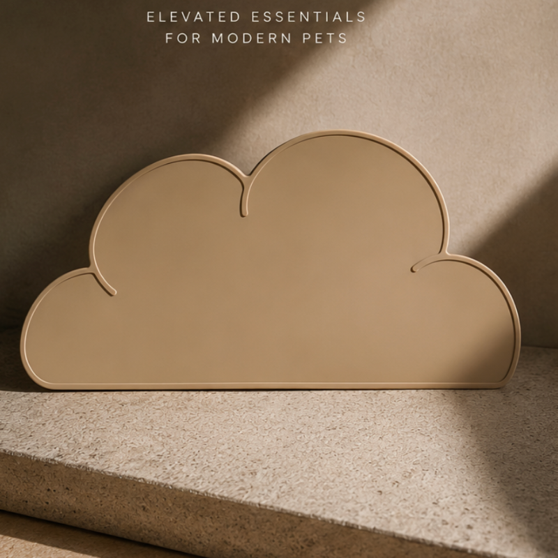 Cloud-shaped pet feeding mat styled in warm editorial lighting on a textured stone surface.
