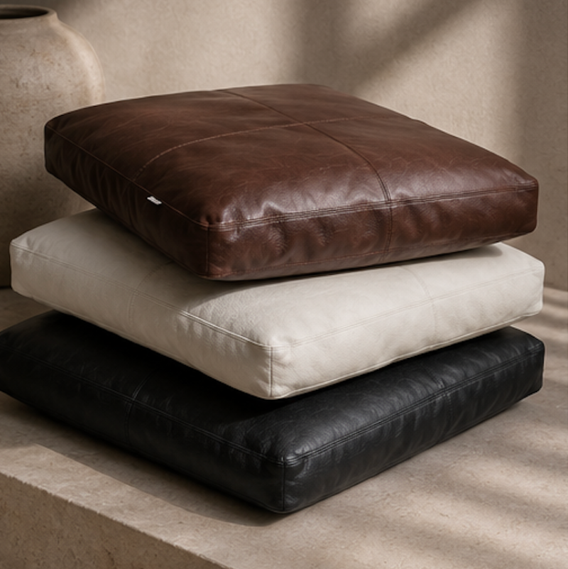 Luxury leather pet beds stacked in espresso, bone and black tones styled in a warm editorial interior.