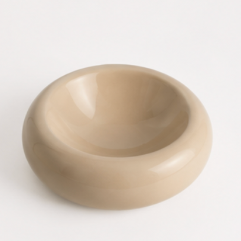 Minimal sand ceramic pet bowl with sculptural rounded shape photographed on a neutral background.