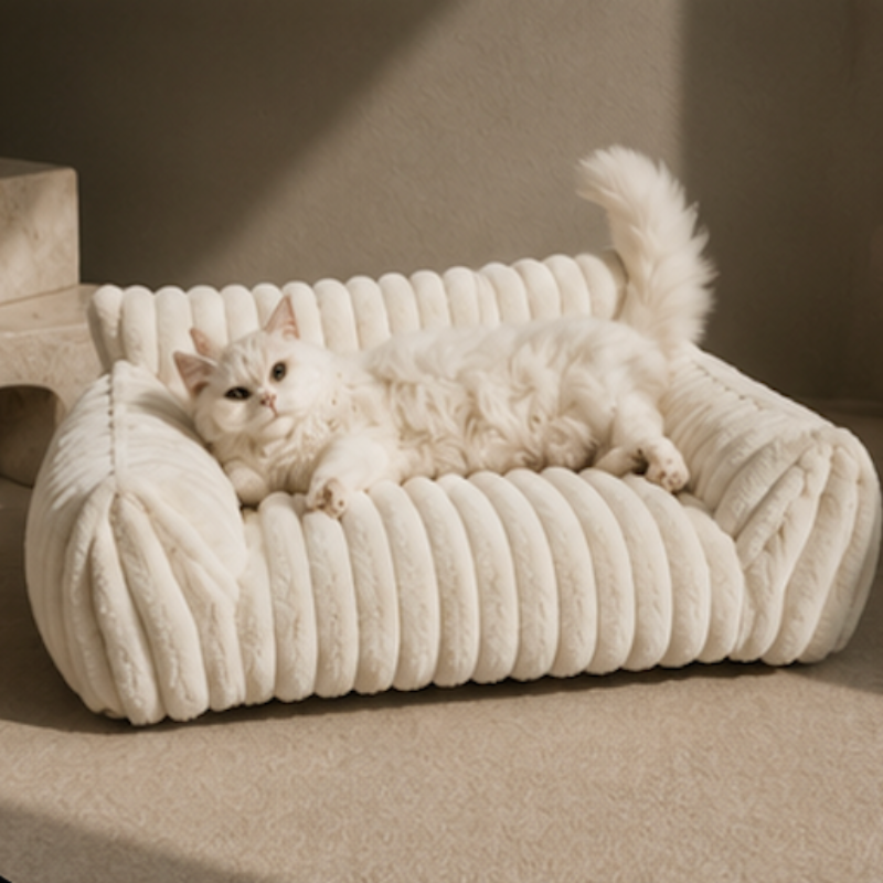 White cat lounging on a textured white pet bed against a neutral background